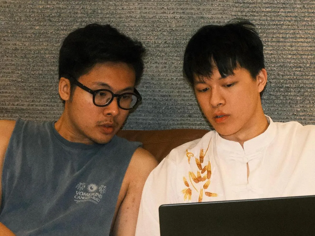 The two founders side by side on a sofa, working over a laptop in the early days