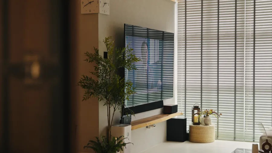 Living room with a wall-mounted screen and timber blinds